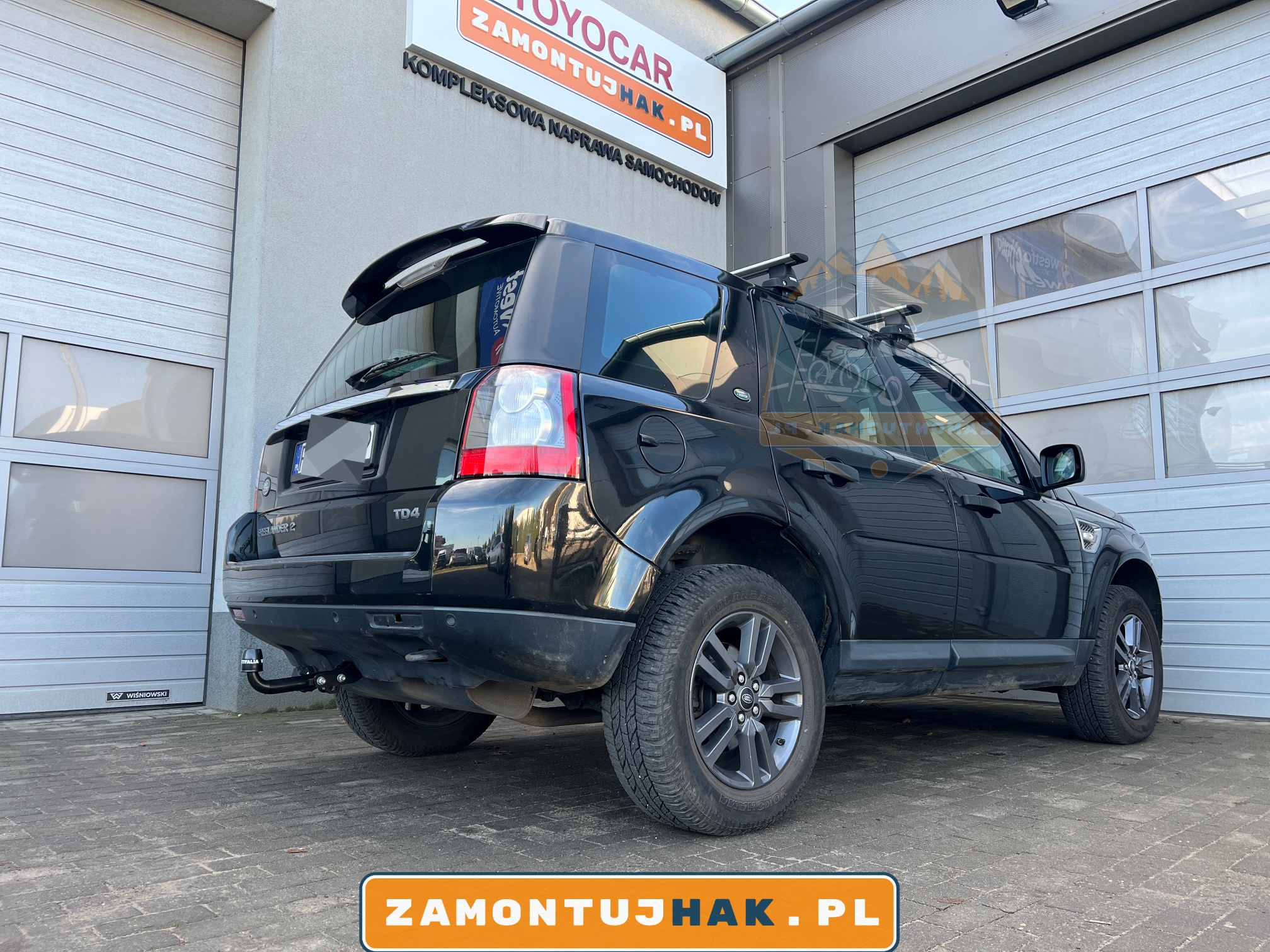 Zdjęcie samochodu Land Rover Freelander z zamontowanym stałym hakiem holowniczym Westfalia f20, zdjęcie zrobiono z tyłu, z prawej strony samochodu na tle serwisu zamontujhak.pl 